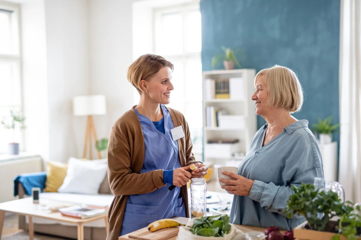 caregiver and an elderly woman preparing a nutritious meal together in a bright kitchen, showcasing meal preparation as an essential personal care service.