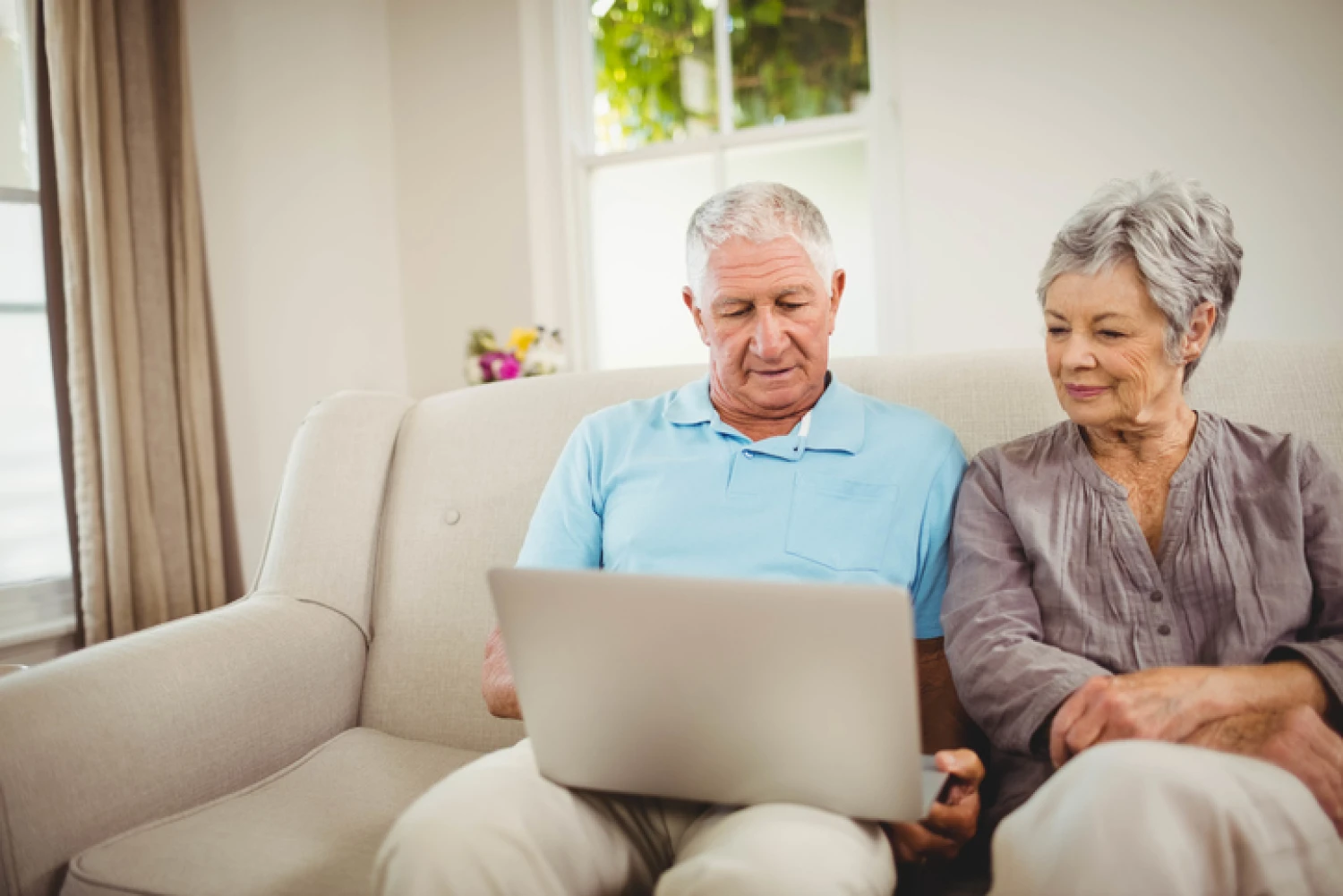Elderly couple using a laptop at home to research and compare home care package providers.