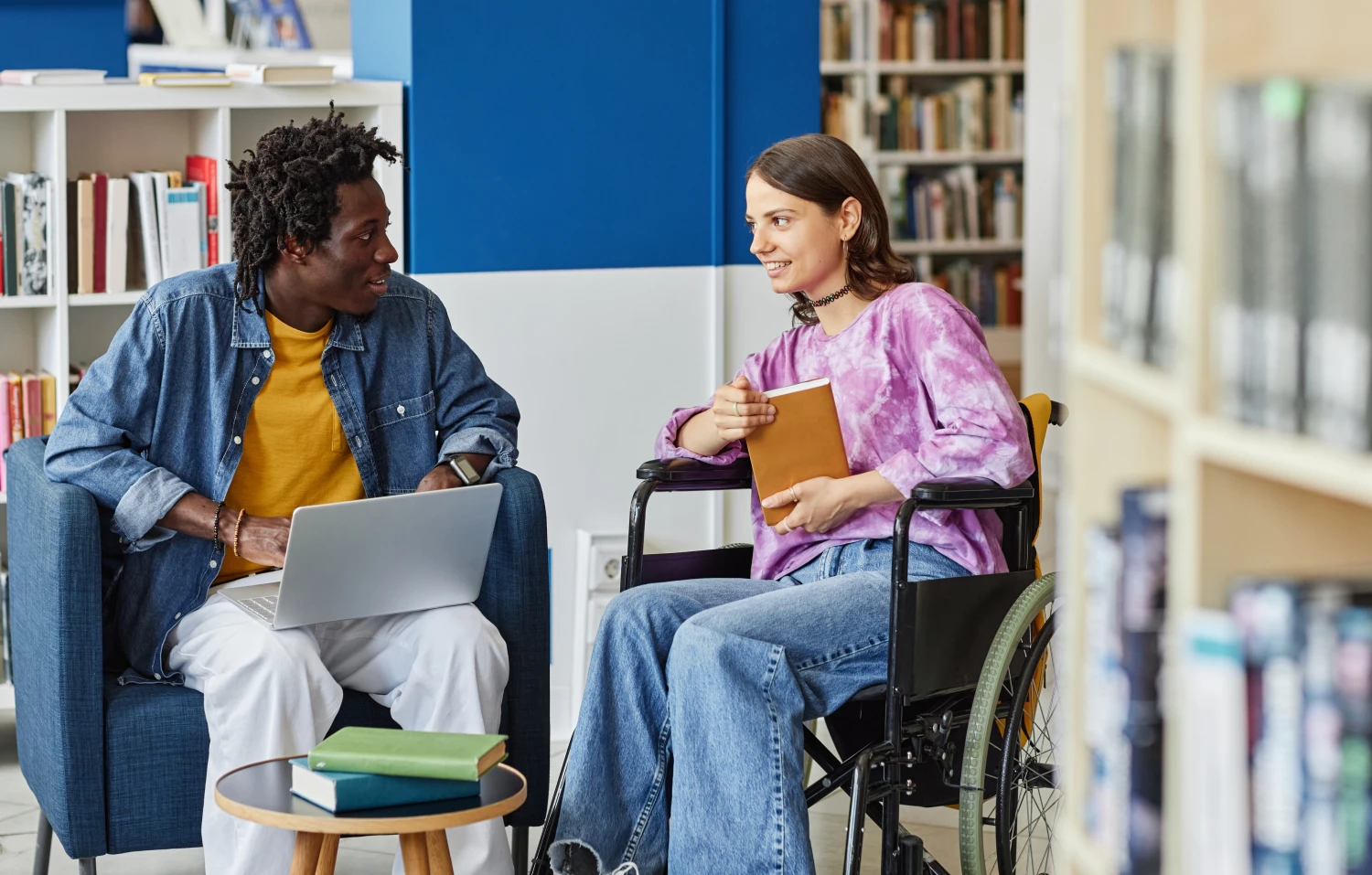 Student with disability studying with friend in library.