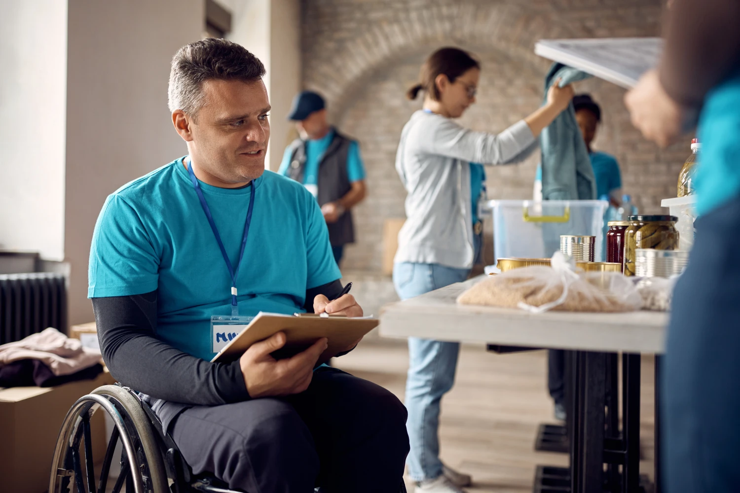 A man in a wheelchair volunteering in a community food bank event.