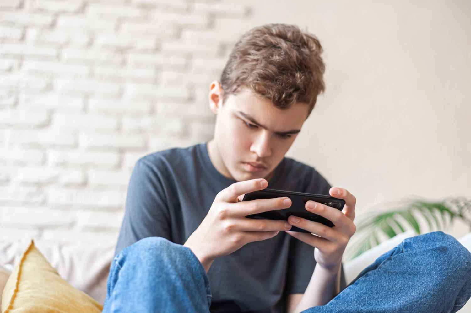 Teenager with signs of autism playing obsessively on phone.