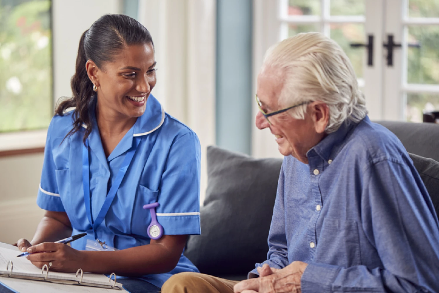 Occupational therapist consulting with elderly man at home, planning personalised care to improve his daily living.