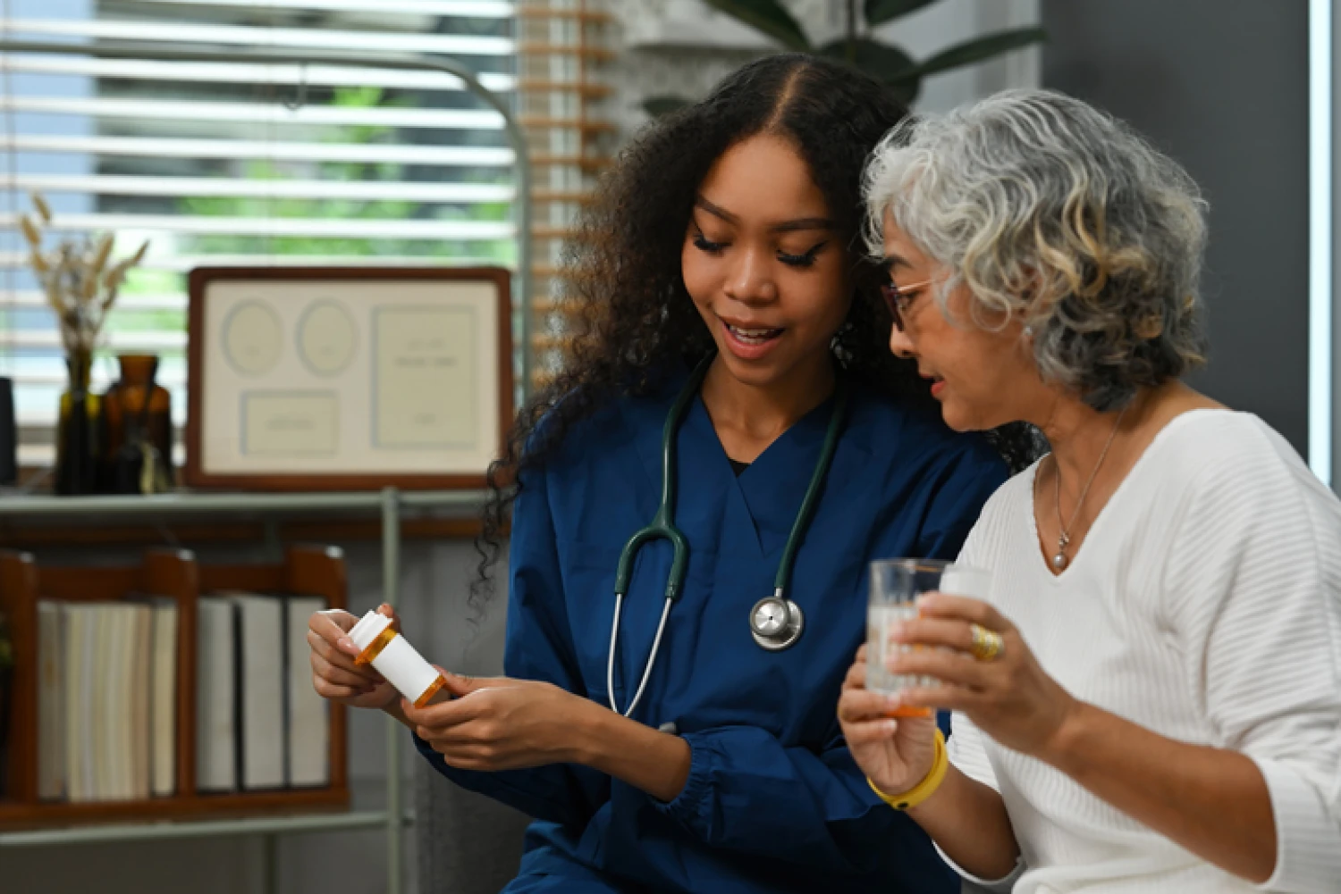 A nurse discusses medication with an elderly woman, representing medical management for Alzheimer's and dementia.