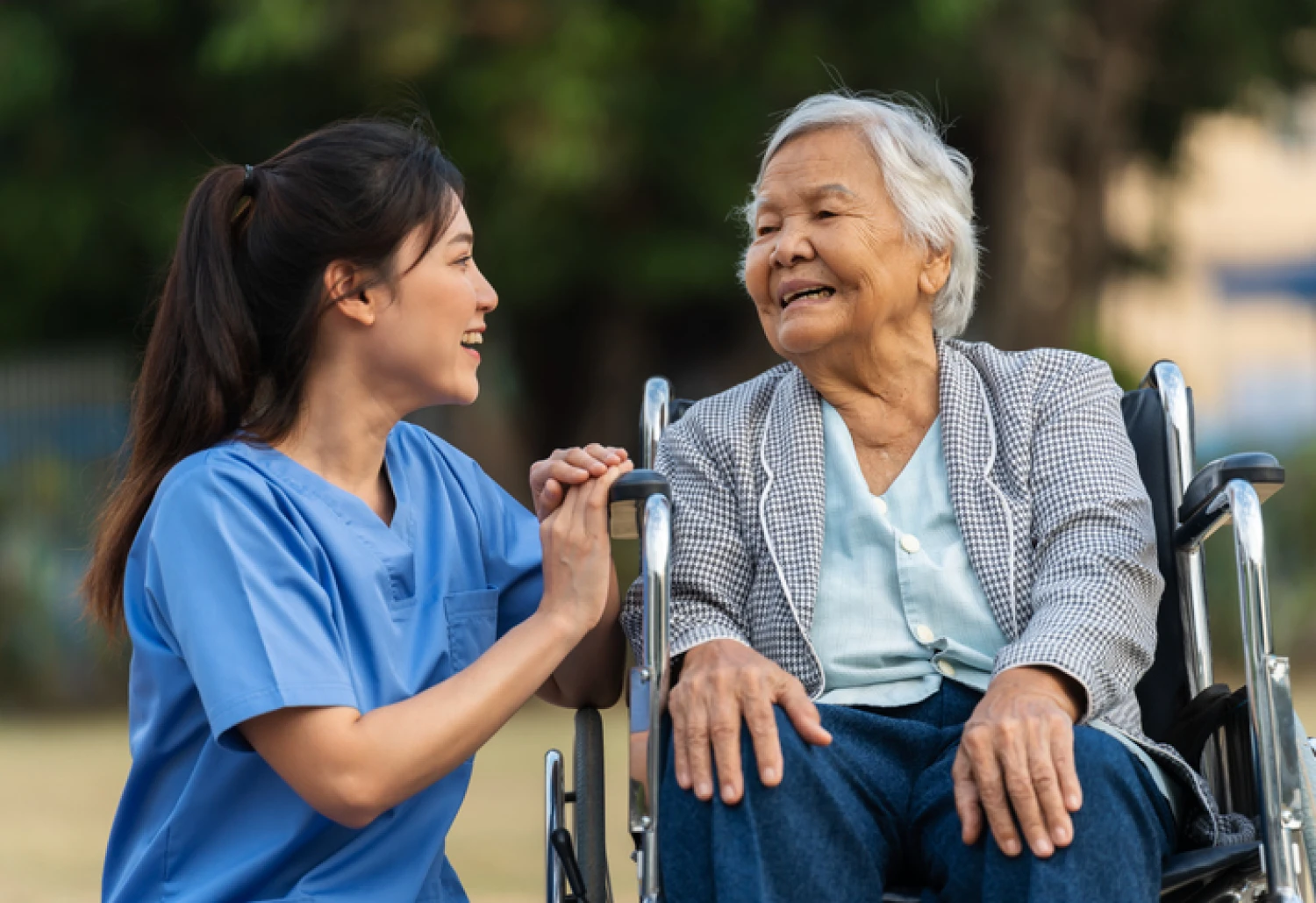 Nurse providing private in-home care to an elderly woman in a wheelchair.