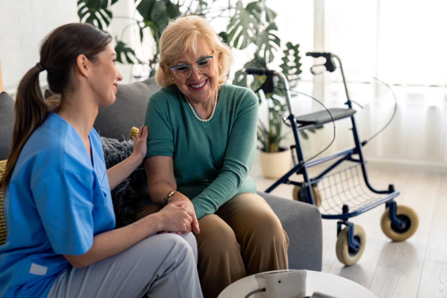 Senior woman smiling and chatting with her caregiver at home, illustrating social support in Level 4 home care.