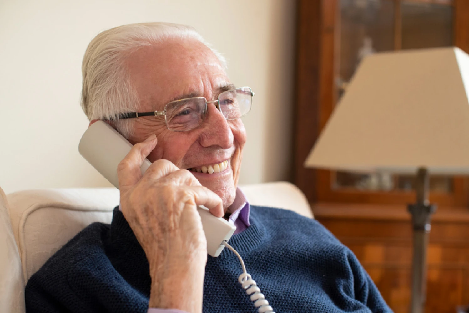 Elderly man smiling while talking on the phone to a home care provider